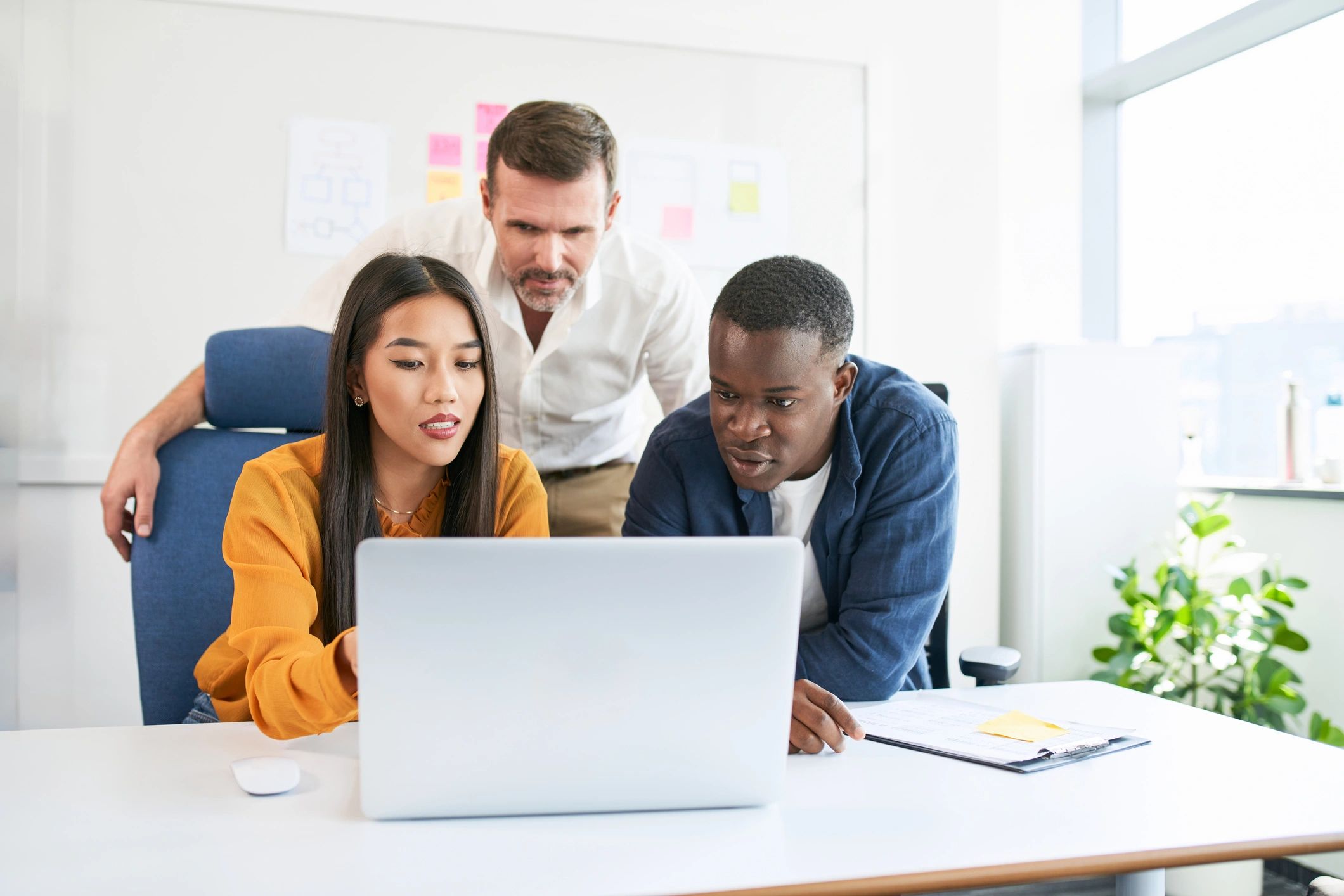 Professionals collaborating around a laptop in a modern office